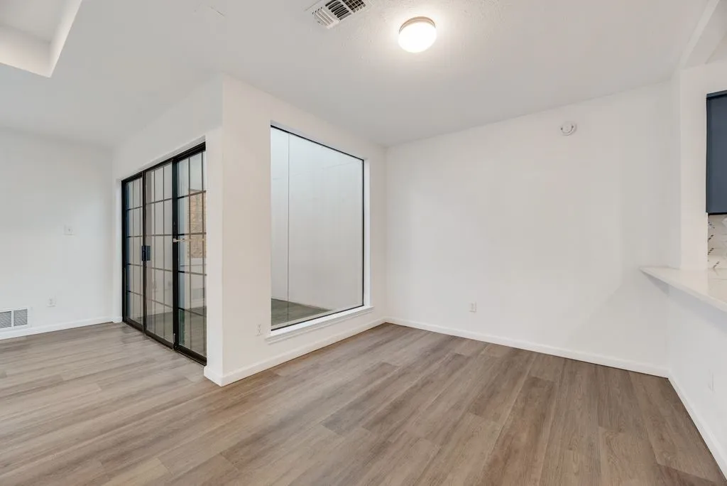 Wood-finish flooring, white walls, and a large window