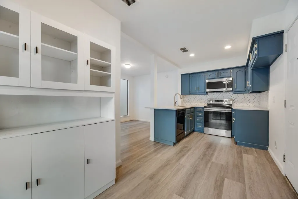 Kitchen featuring stainless steel appliances, blue cabinetry, light countertops, and a decorative tile backsplash