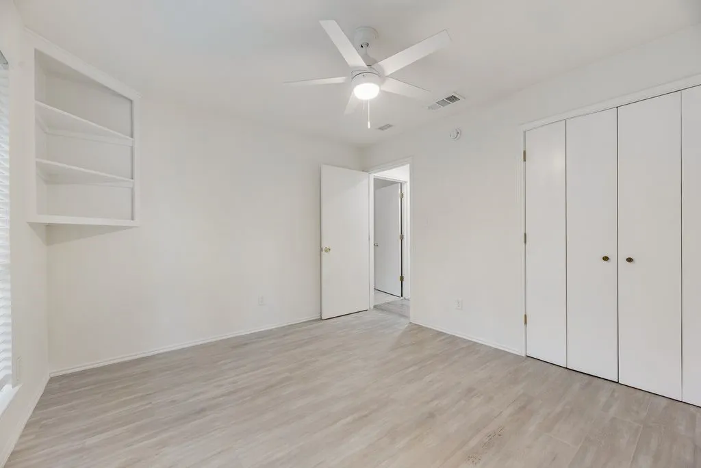 Built-in shelving, ceiling fan with integrated lighting, wood-finish flooring, and bi-fold closet doors