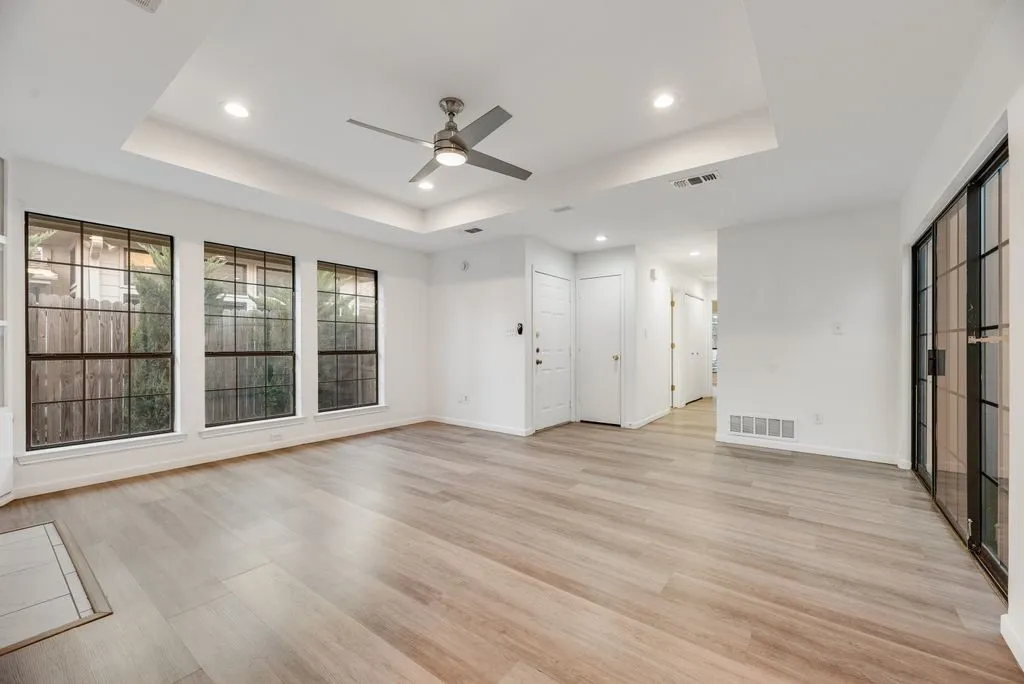 Spacious interior with wood-finish flooring, recessed lighting, ceiling fan, and multiple windows