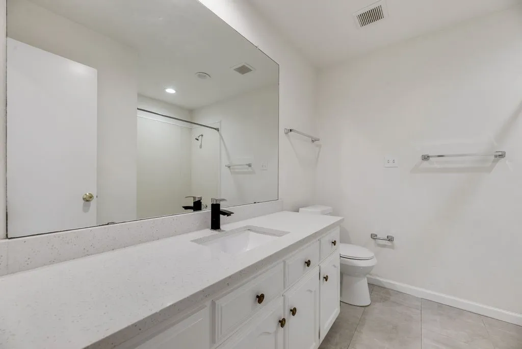 Integrated vanity with white cabinetry, a single basin sink, and a black faucet