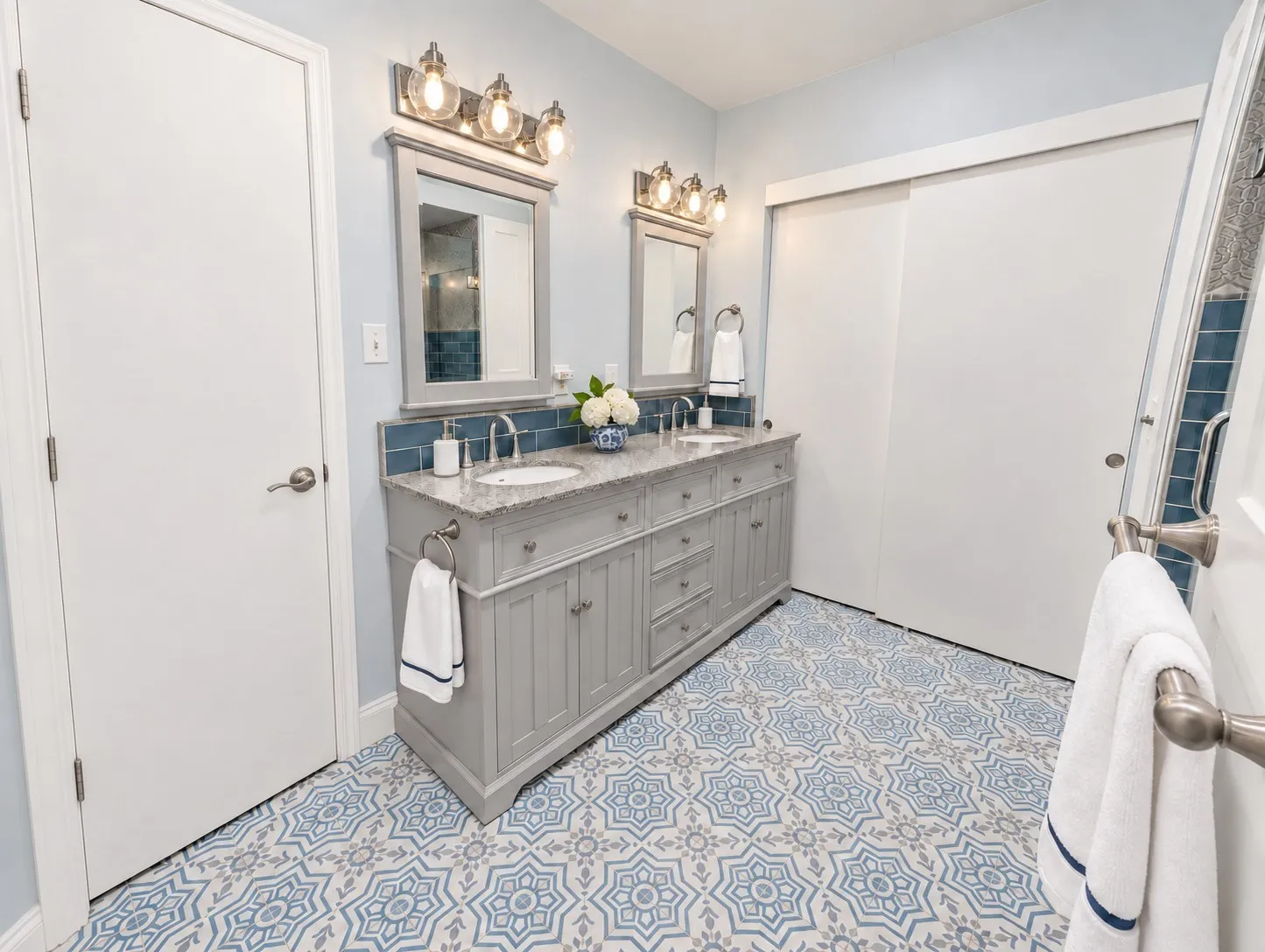 Dual vanity with integrated sinks, granite countertop, and gray cabinetry