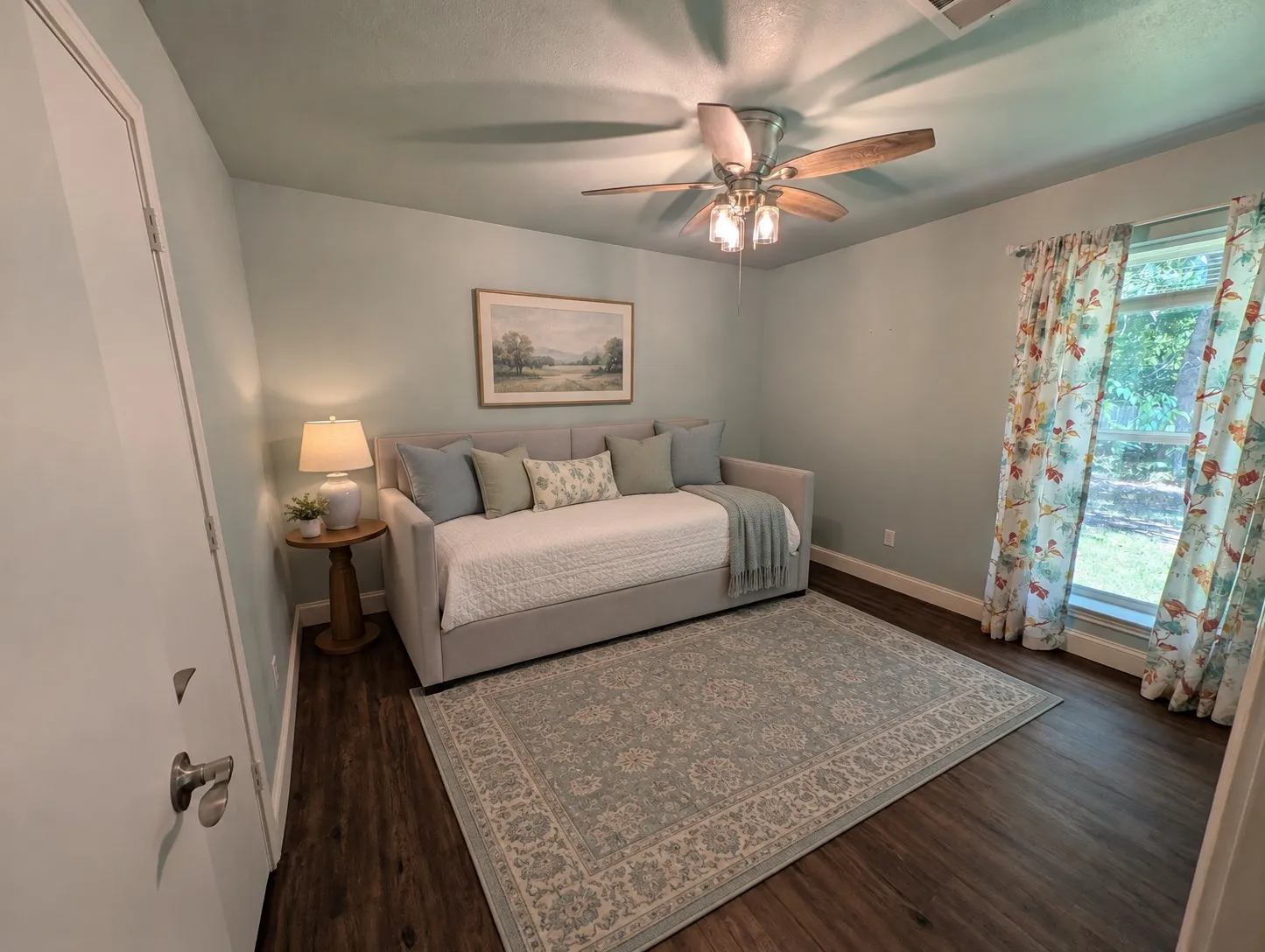 Room featuring wood-finish flooring, a ceiling fan with integrated lighting, and a large window