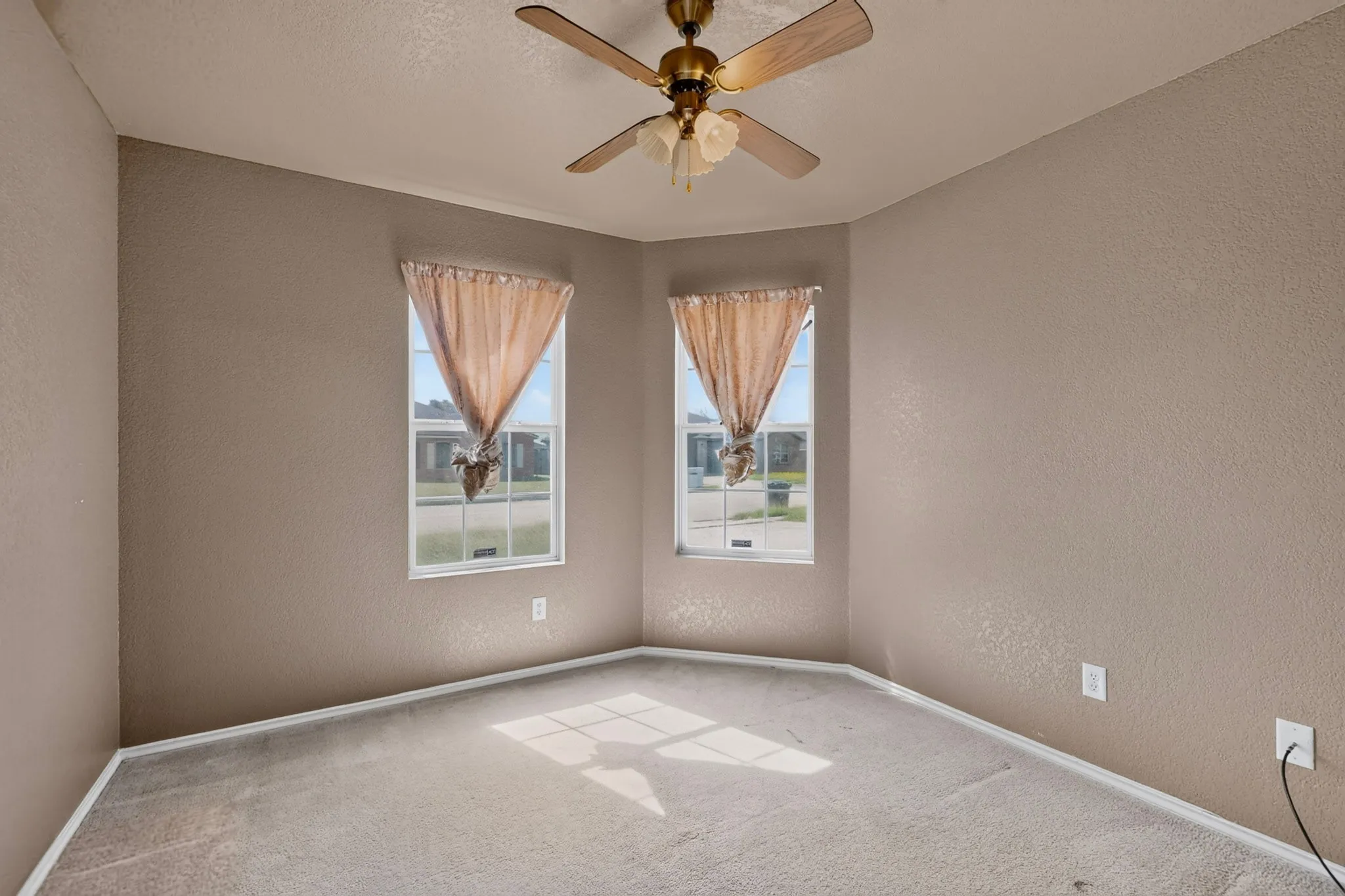 Neutral carpet flooring, textured walls, and a ceiling fan with integrated lighting