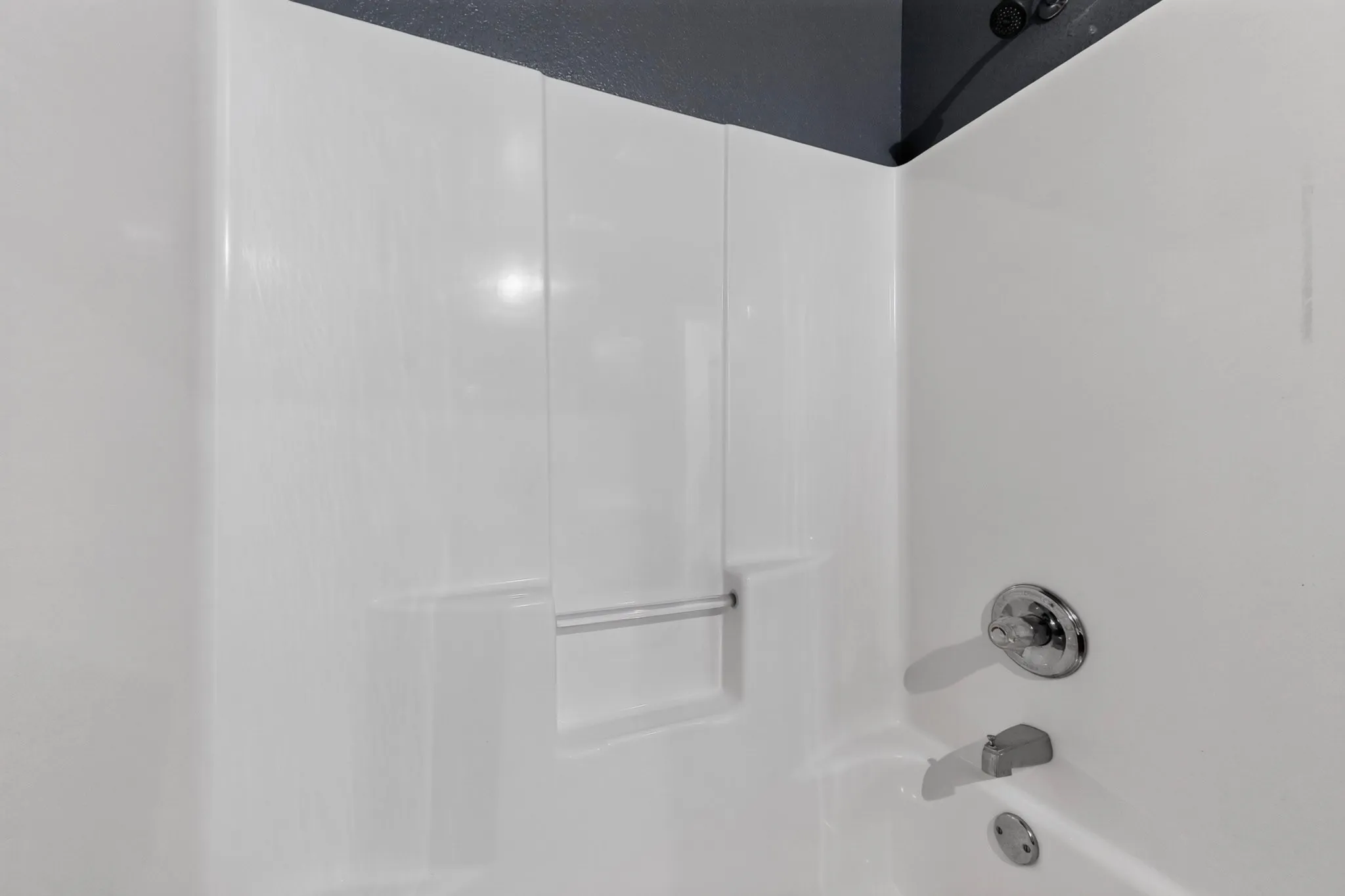White shower surround with integrated shelving and chrome fixtures