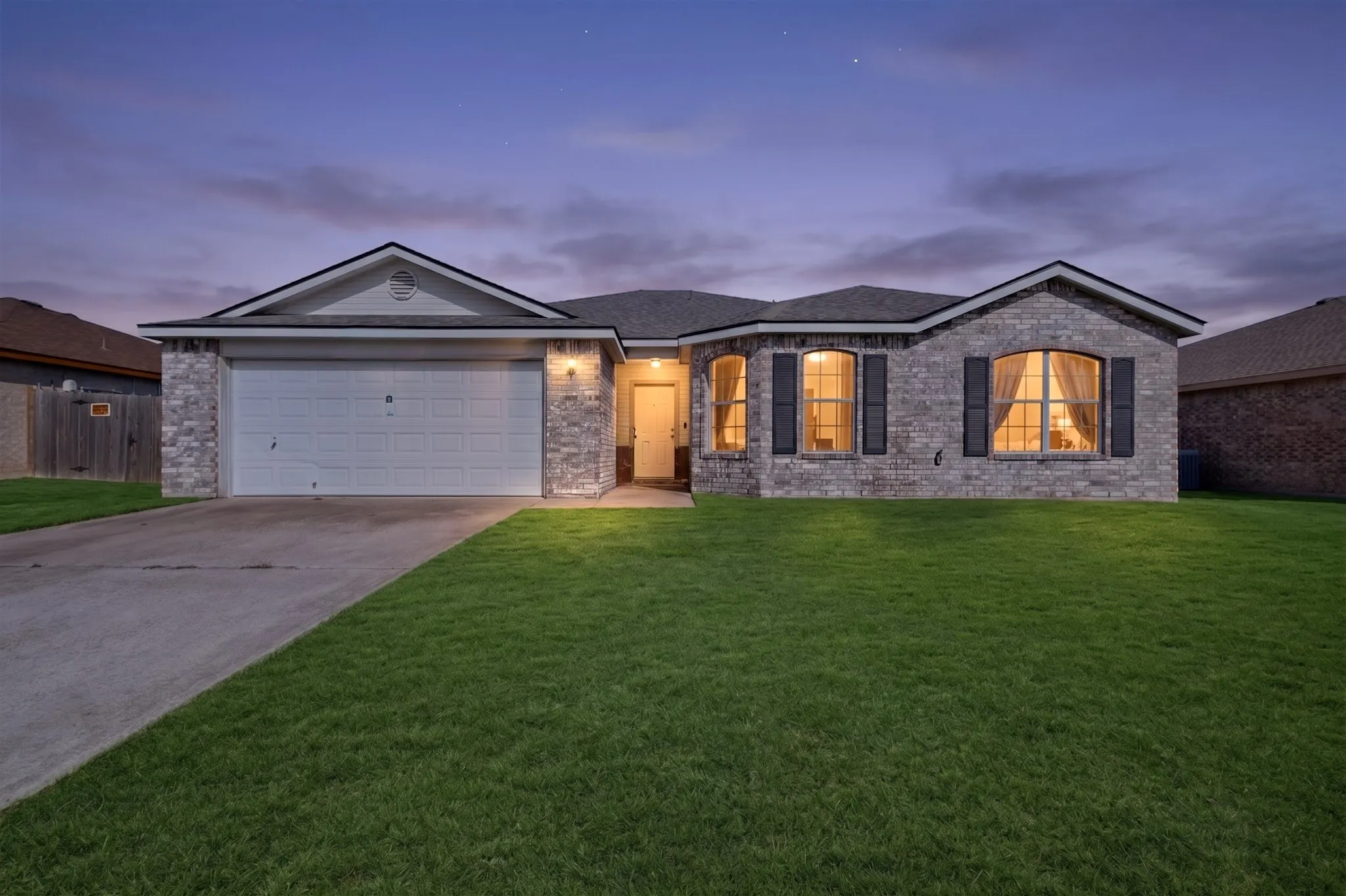 Brick veneer exterior with stone accents, attached garage, curved bay windows, and front lawn