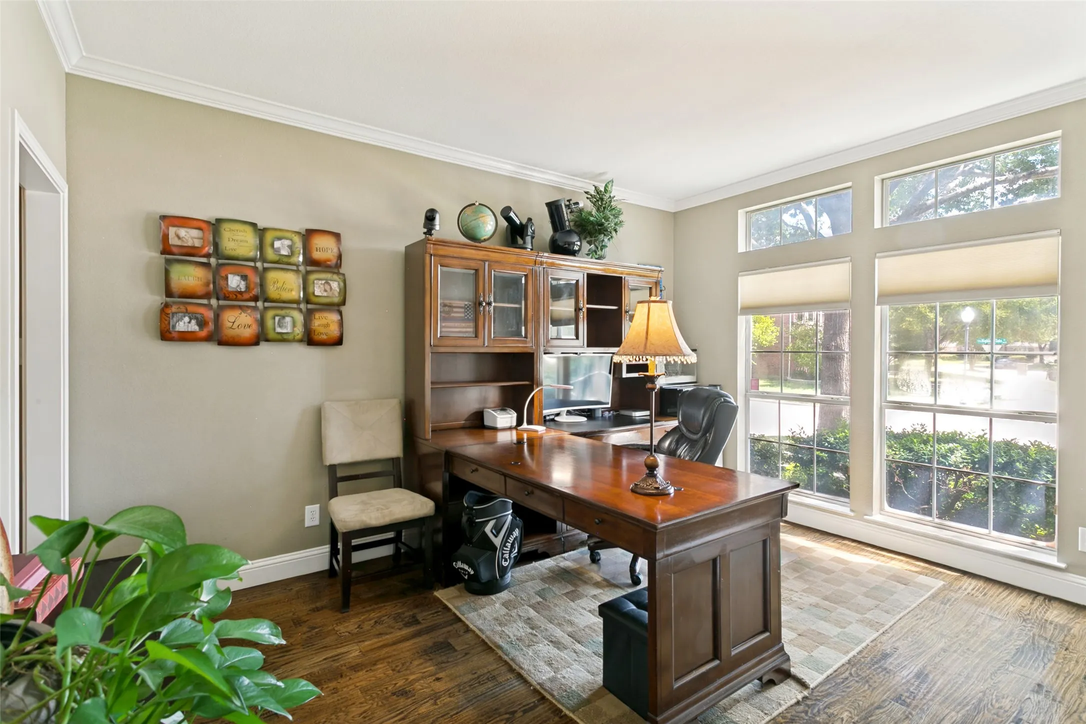 Crown molding, large picture windows, transom windows, and neutral wall tones accentuate office or den.