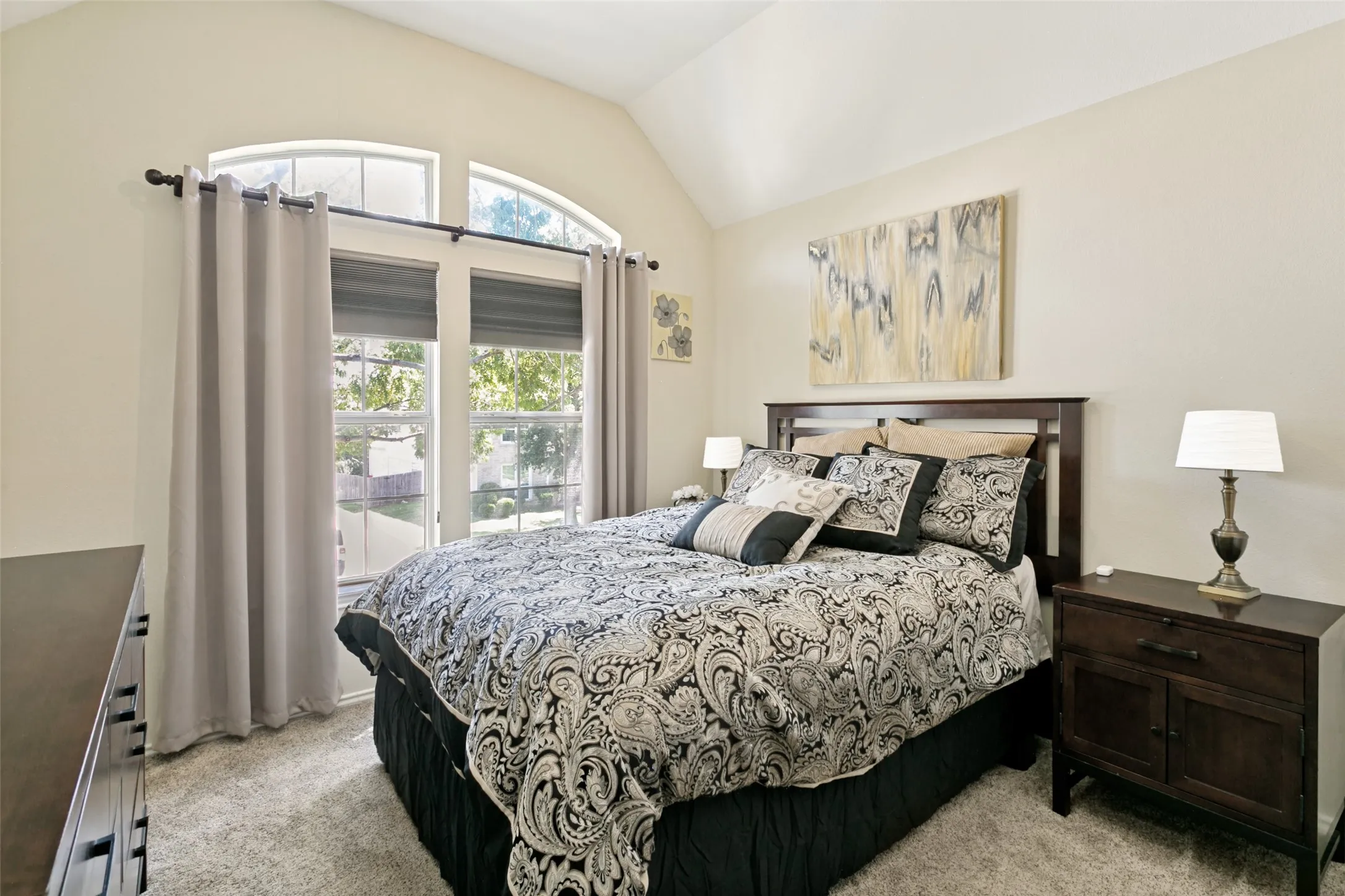 Upstairs bedroom with Vaulted ceiling, dual arched transom windows, two-pane window unit, and light-tone carpet flooring