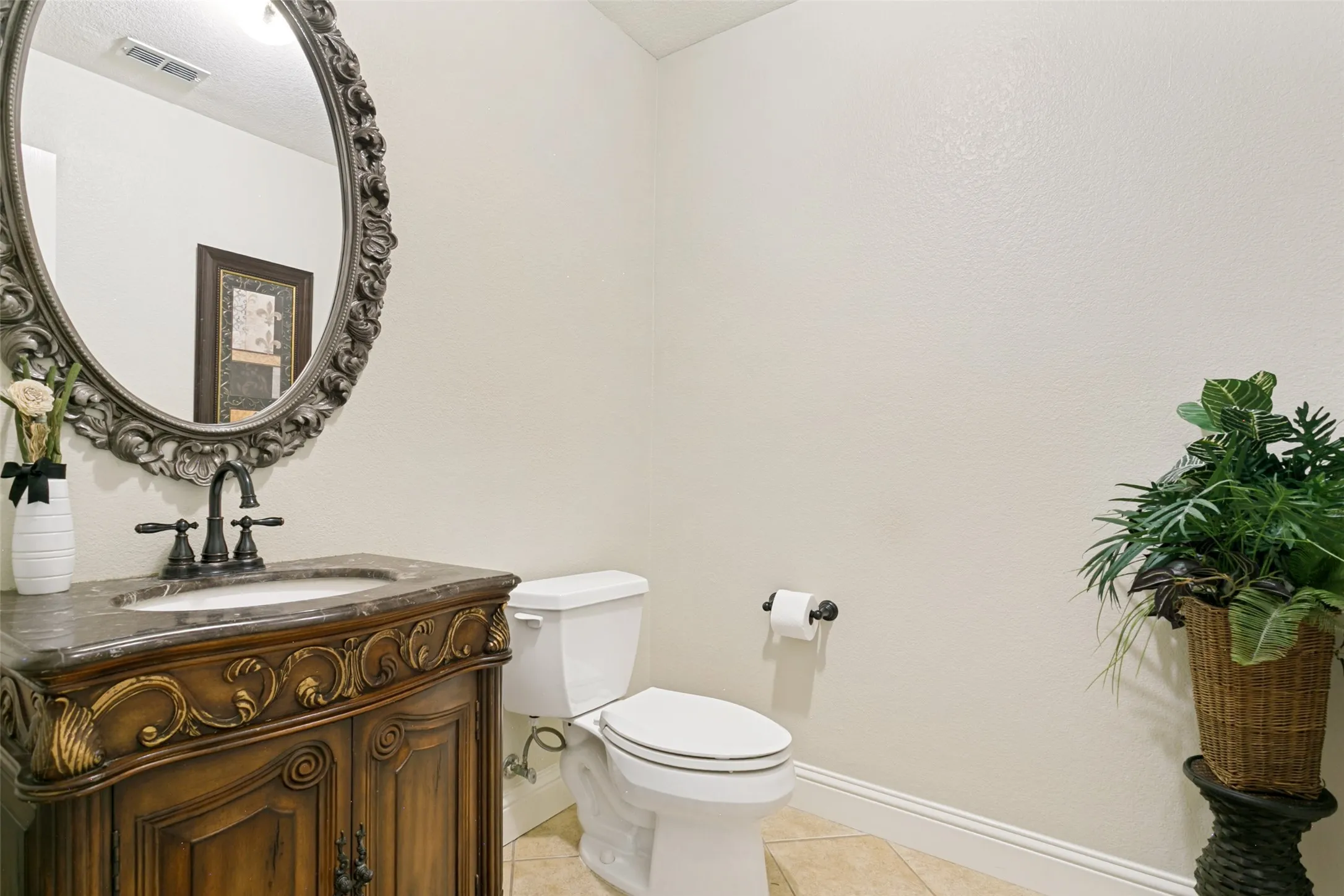 Downstairs half bath with Ornate vanity and carved wood details, a stone countertop, and a vessel sink with a dark-finish faucet