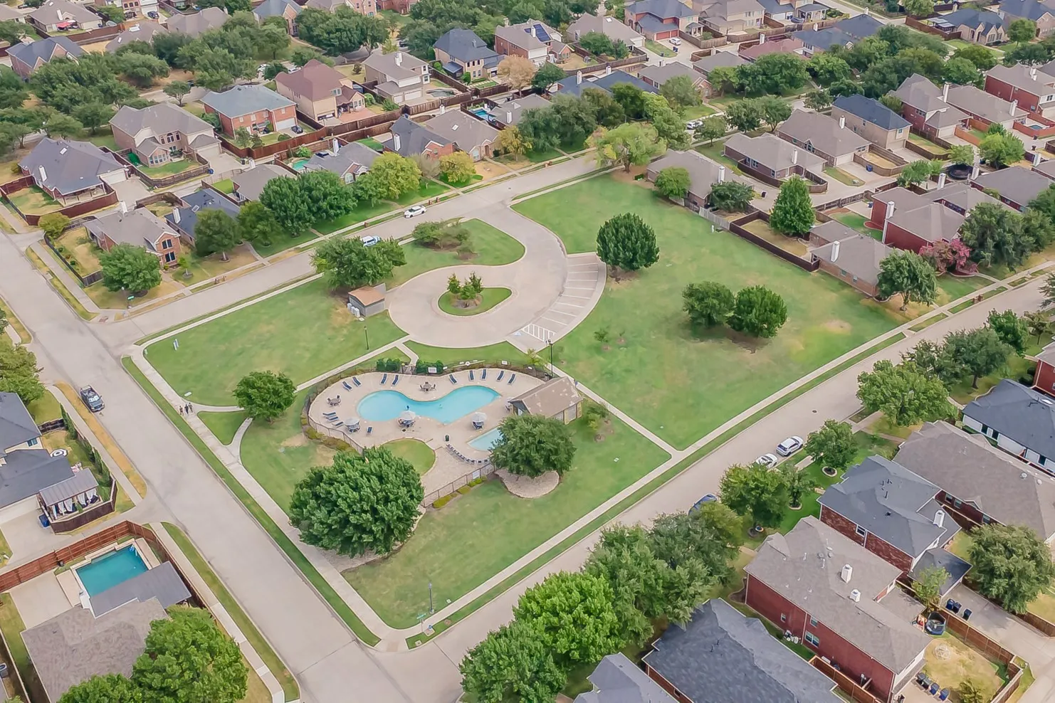 Community park with a freeform swimming pool, integrated spa, and surrounding lounge seating
