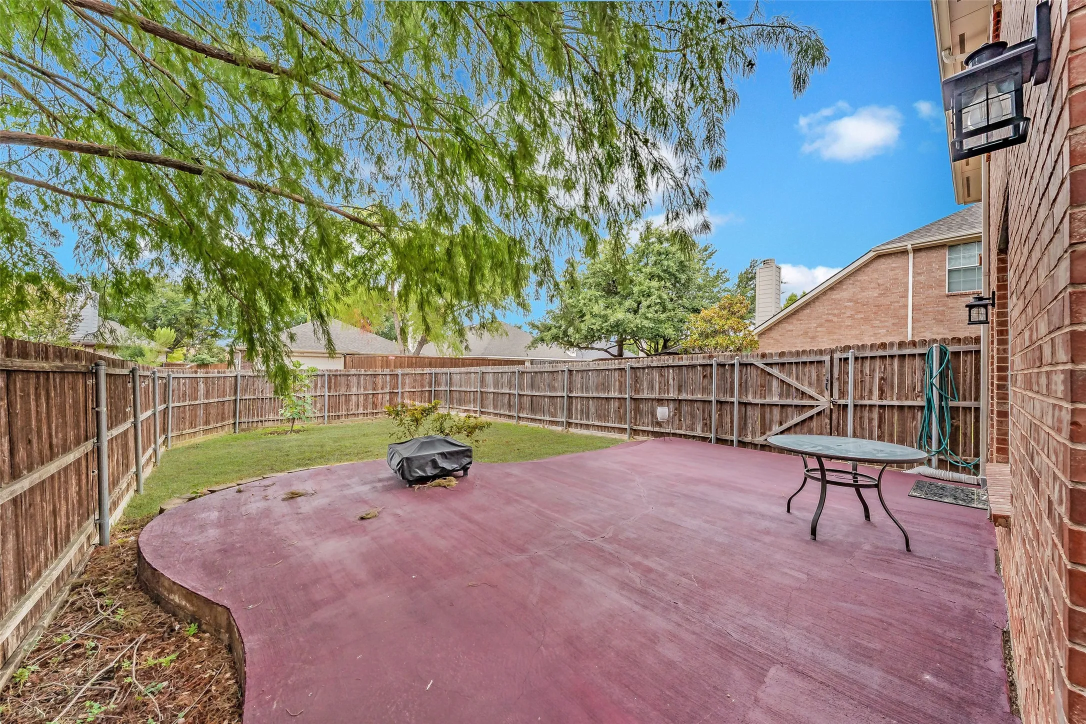 Expansive backyard featuring a stained concrete patio, a manicured lawn, and a perimeter wooden fence