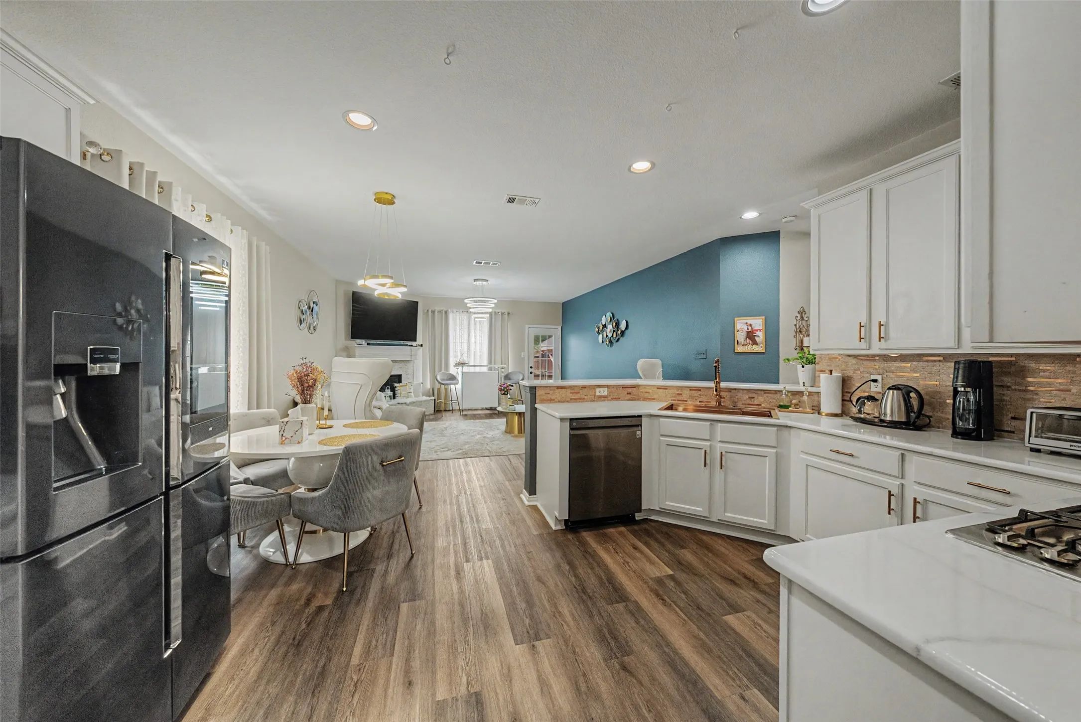 Kitchen featuring white cabinetry, quartz countertops, a tile backsplash, and wood-finish flooring