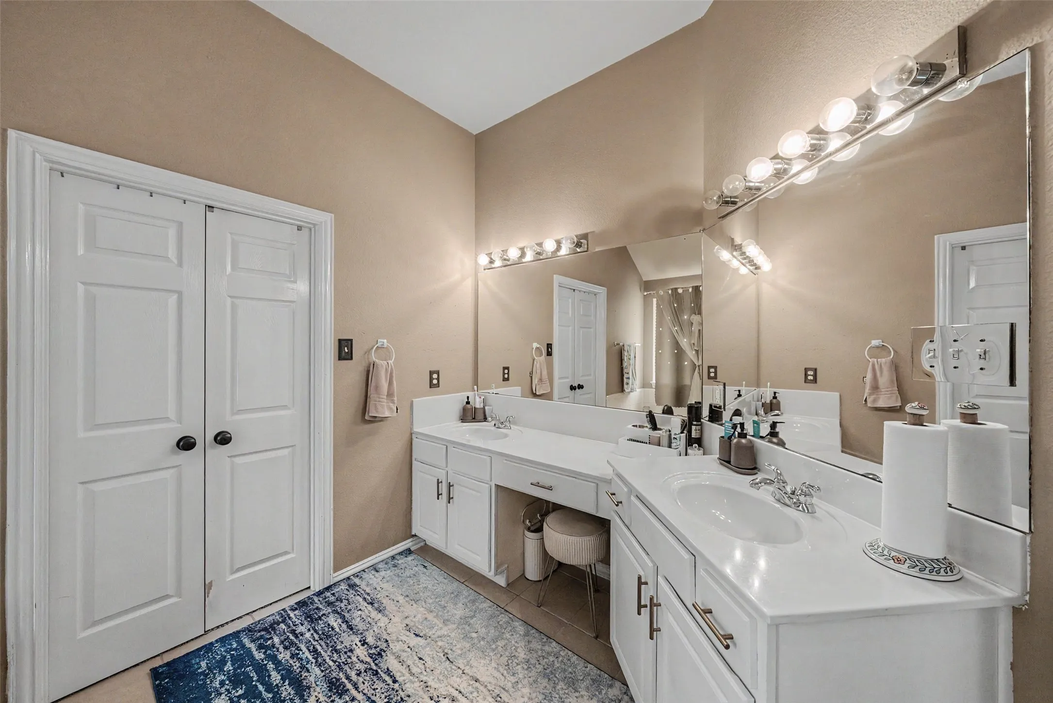 Dual-sink vanity with white cabinetry, integrated countertop, and an extended wall mirror