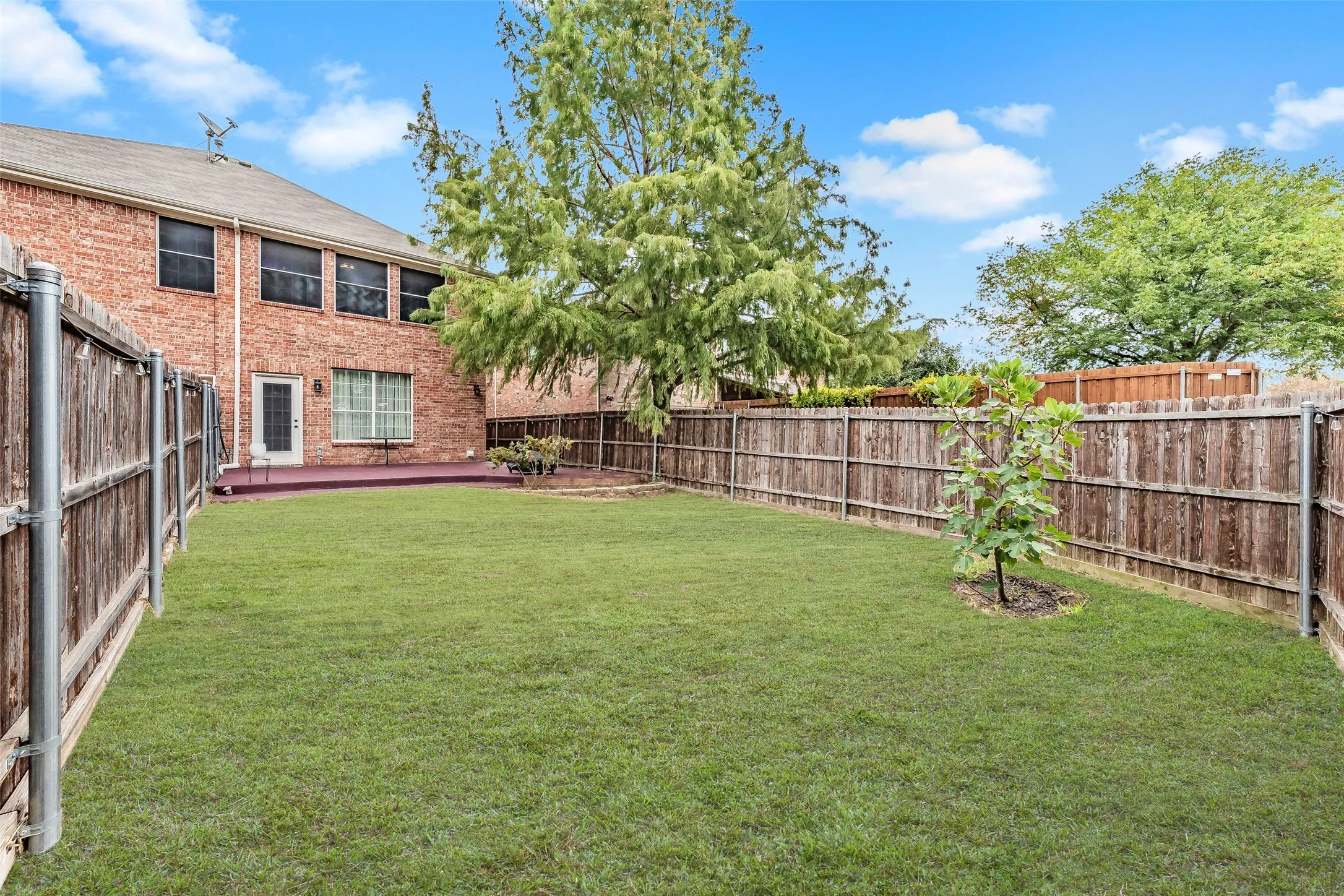 Expansive backyard with a manicured lawn, full wood fencing, and mature trees