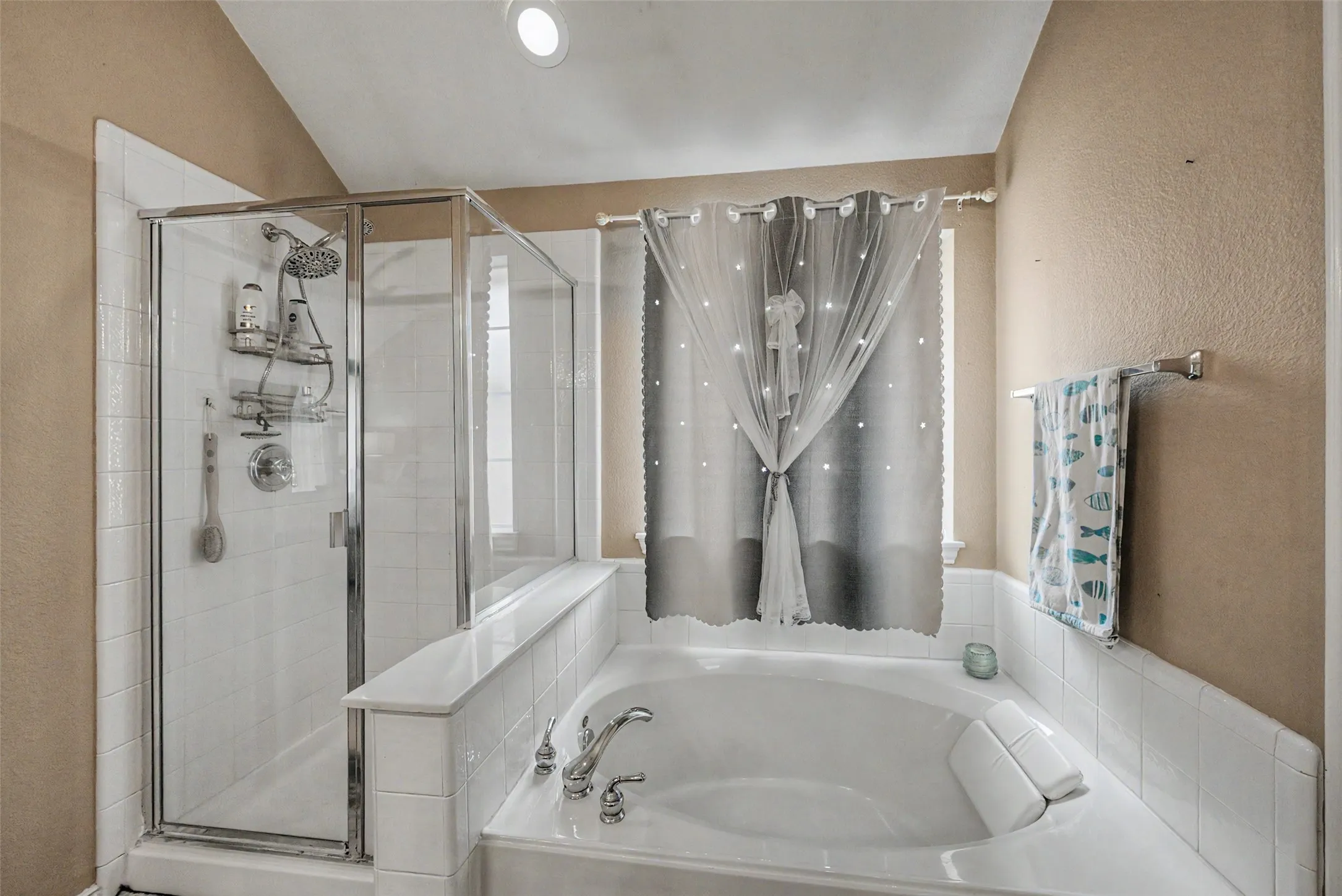 Recessed lighting with a glass-enclosed shower, featuring a multi-function showerhead, and a built-in tub