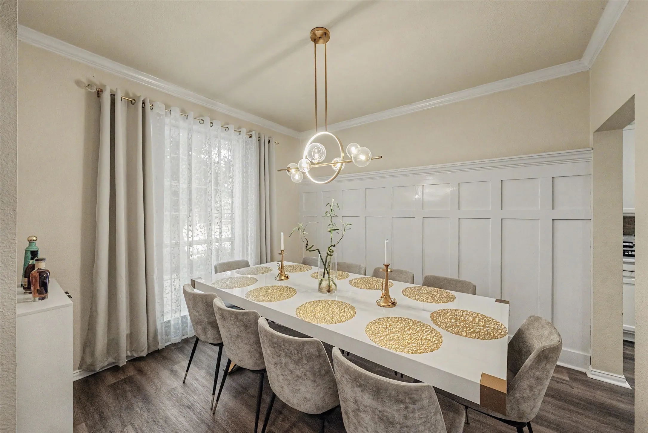 Wood-finish flooring, accent wall paneling, crown molding, and a modern ceiling light fixture