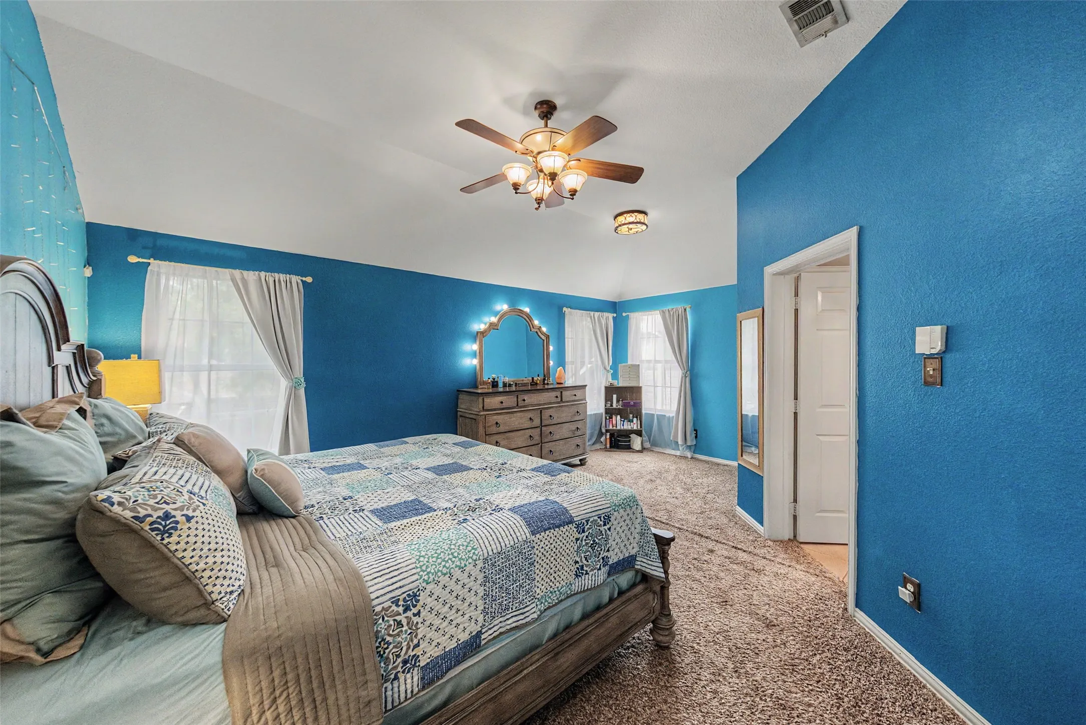 Vaulted ceiling with ceiling fan, neutral carpet flooring, and white trim