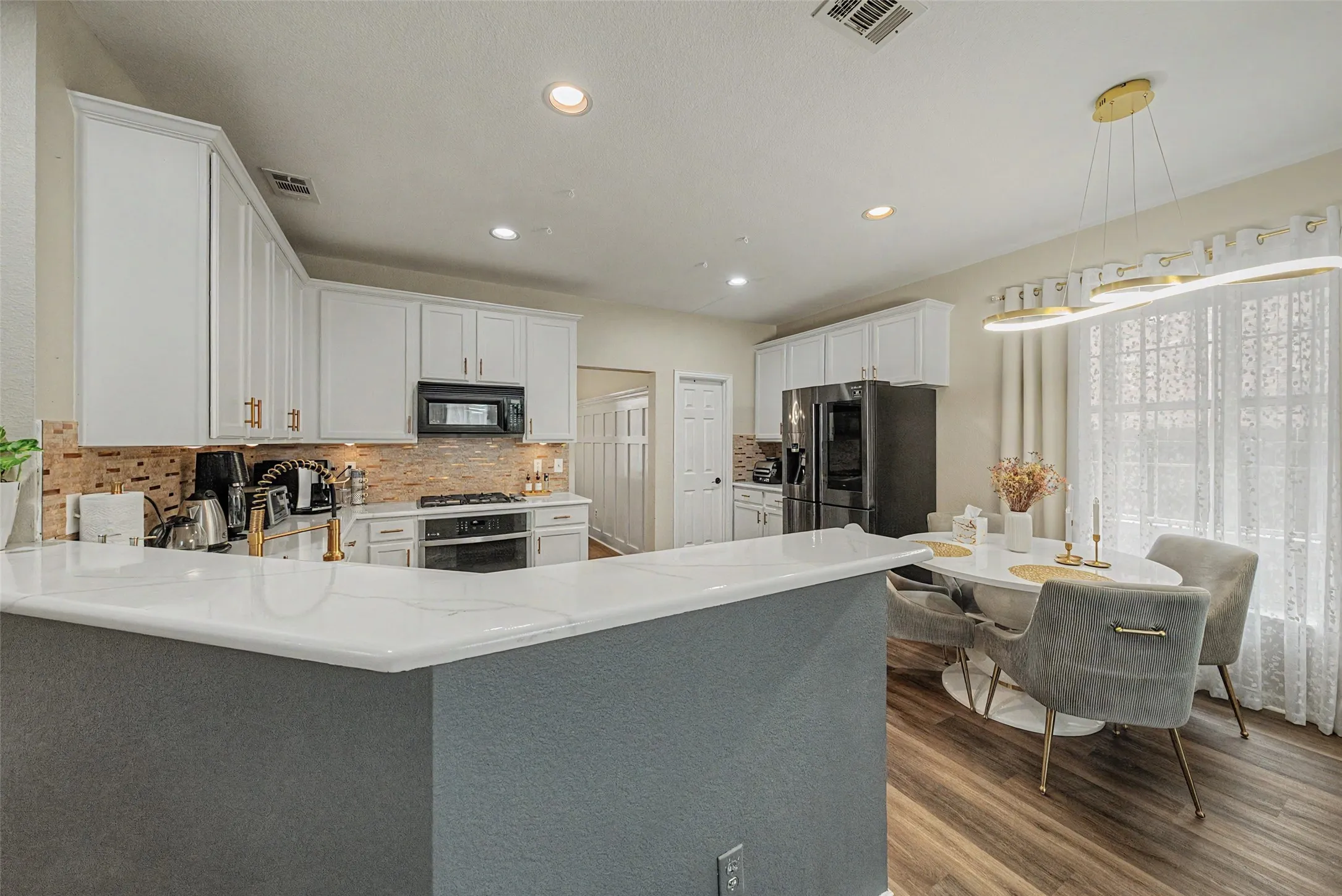 Kitchen featuring white cabinetry, a tile backsplash, and a black appliance package
