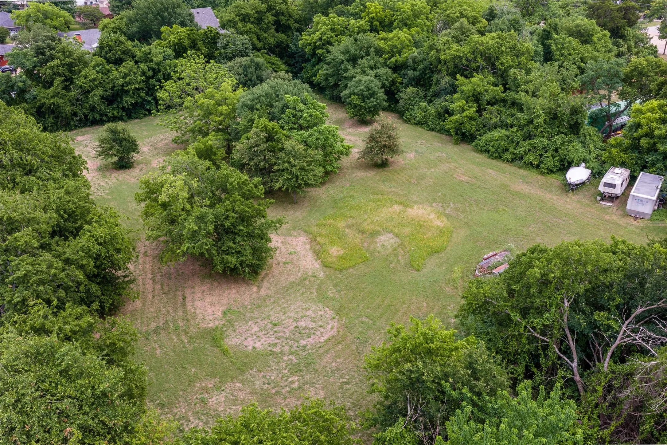 Expansive green space featuring mature trees and partial tree cover
