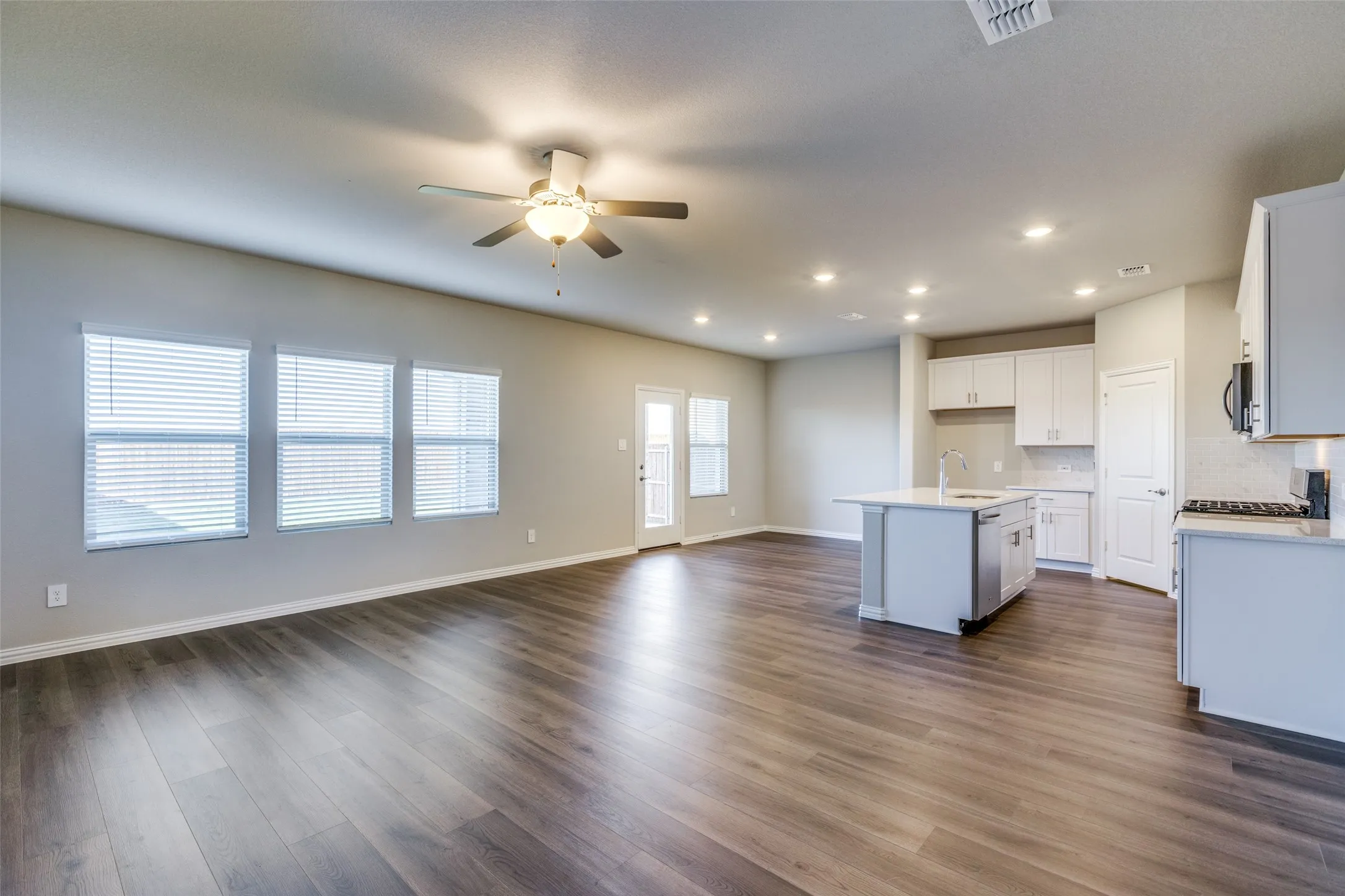 Kitchen featuring an island with sink, white cabinets, dark hardwood / wood-style flooring, ceiling fan, and sink