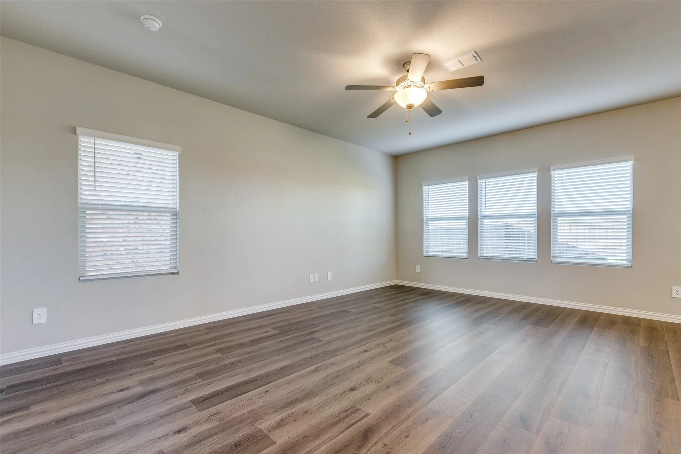 Spare room featuring a wealth of natural light, ceiling fan, and dark wood-type flooring