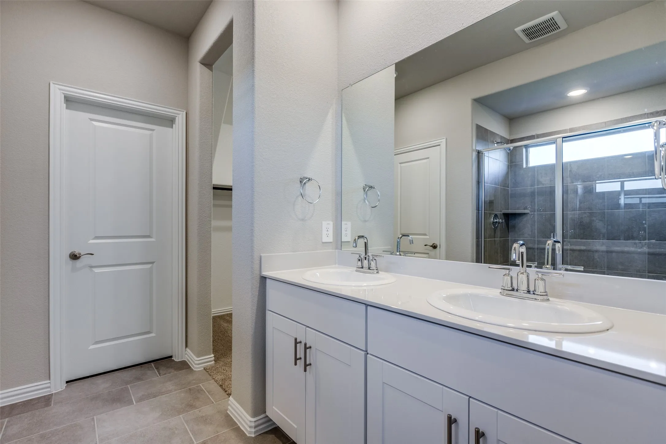 Bathroom with walk in shower, vanity, and tile patterned flooring