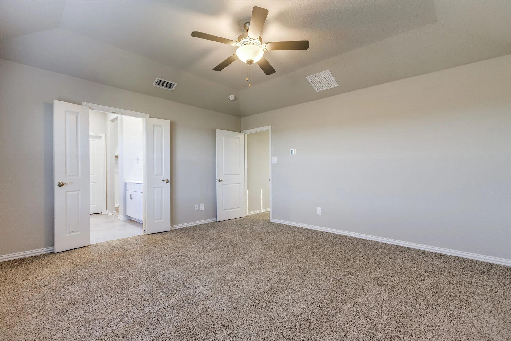 Unfurnished bedroom featuring ceiling fan, light colored carpet, and lofted ceiling