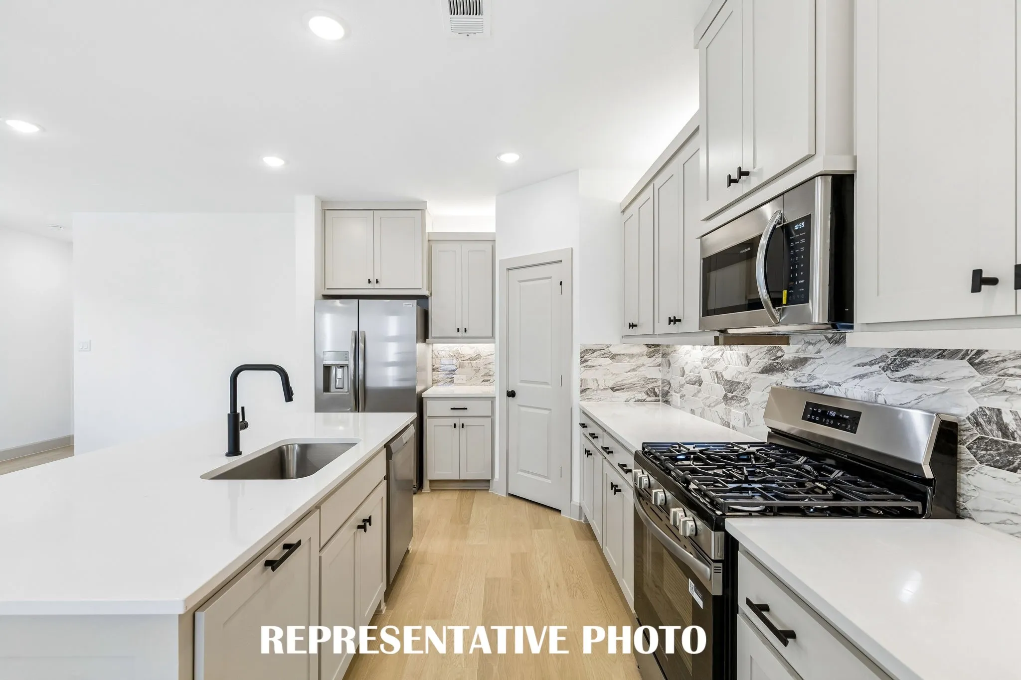 Beautiful cabinetry, gorgeous counter tops and classic backsplash effortlessly pair with contemporary stainless steel to create a kitchen for the ages!  REPRESENTATIVE PHOTO