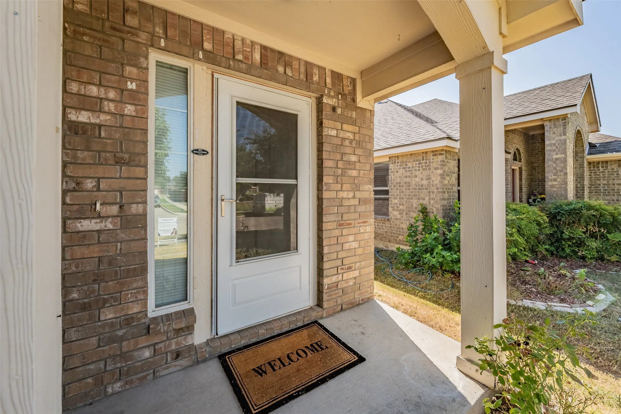 Brick exterior with a covered porch and concrete flooring