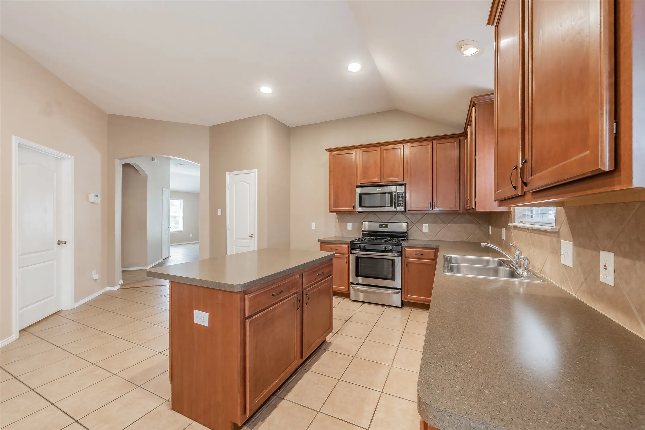 Kitchen featuring a center island, stainless steel appliances, tile flooring, and wood cabinetry