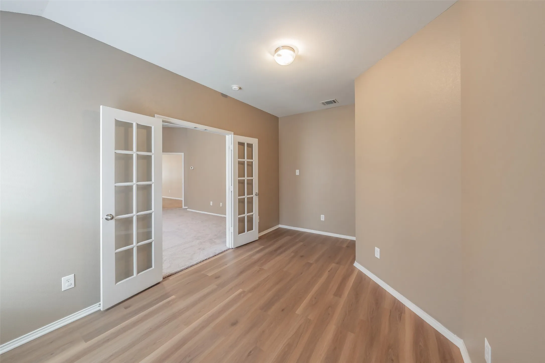 Wood-finish flooring, neutral wall tones, and overhead lighting