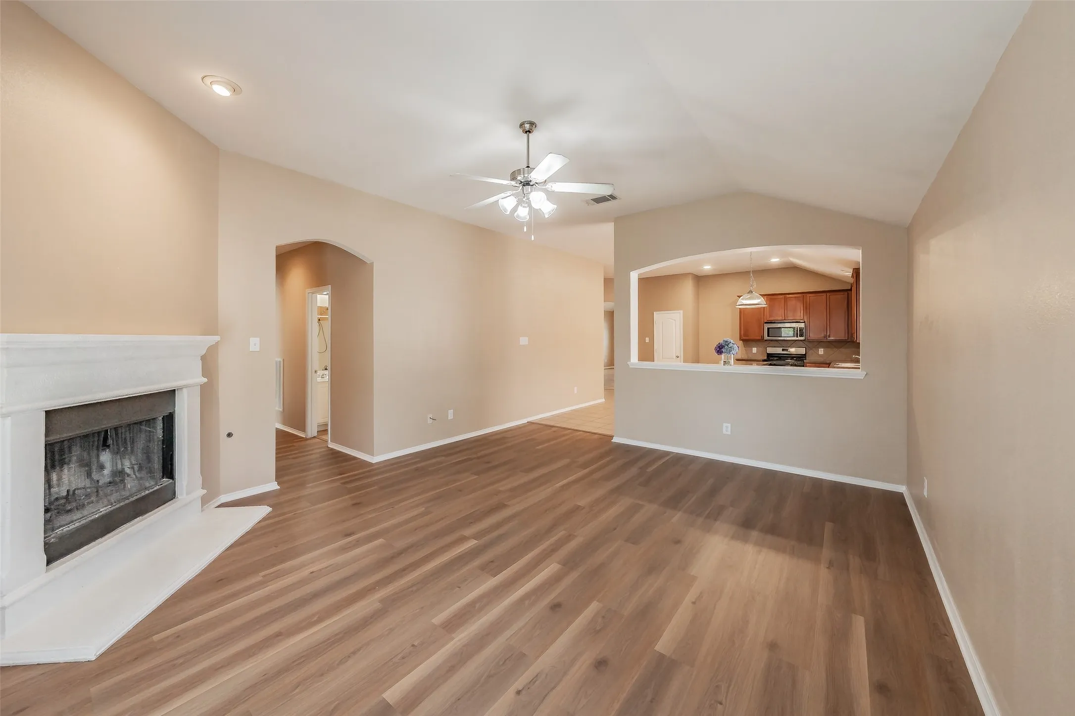 Wood-finish flooring throughout, living area with a fireplace, vaulted ceiling, and recessed lighting