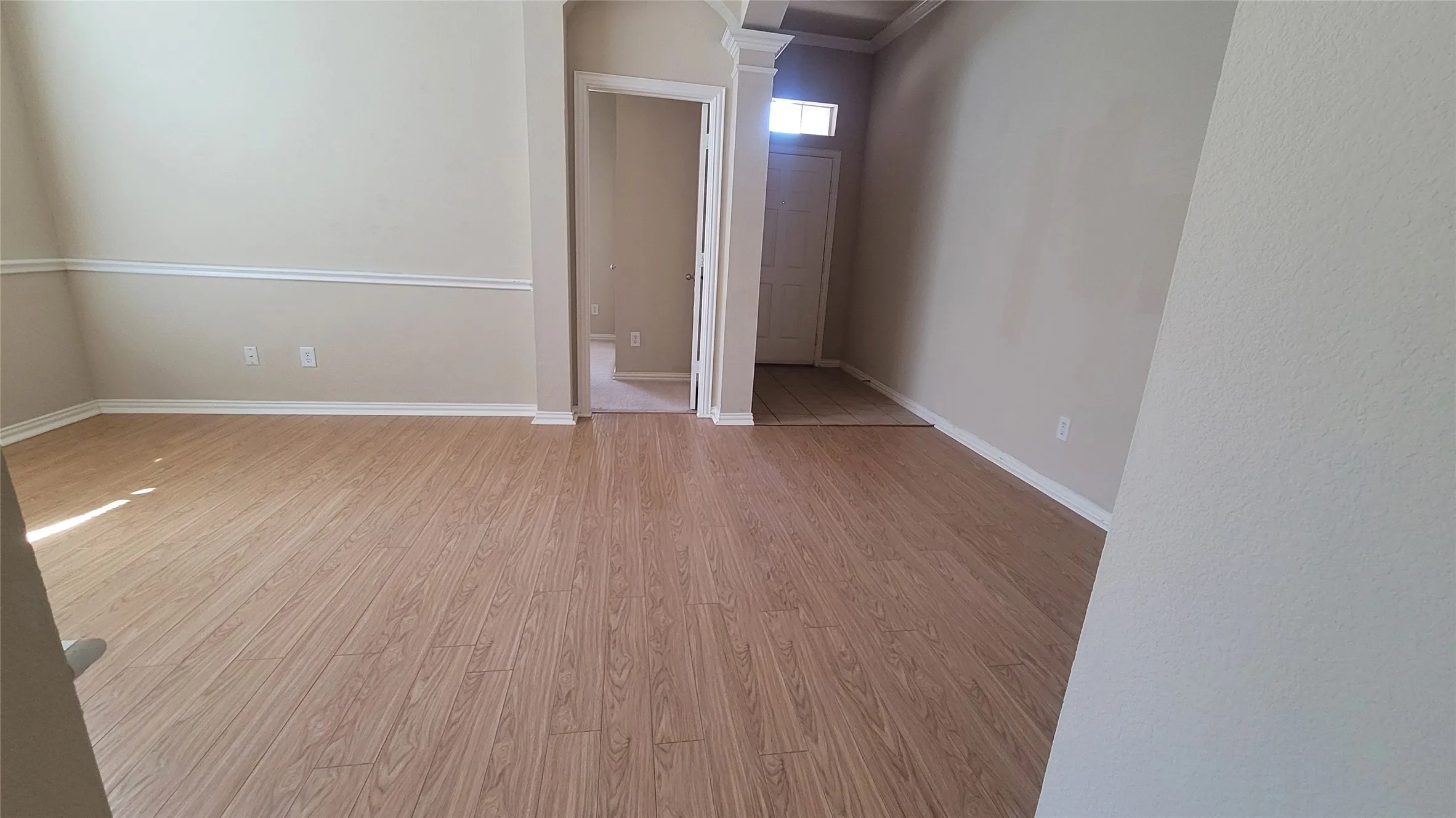 Wood-finish flooring throughout, neutral wall paint, white crown molding, and white baseboards