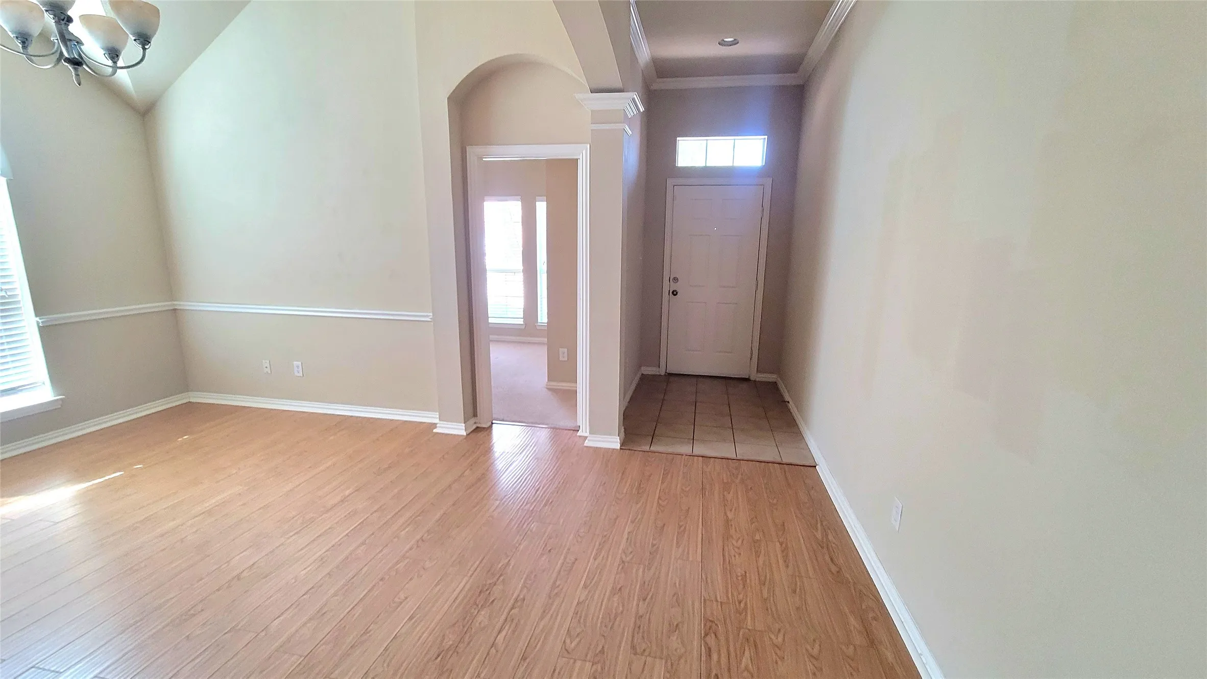 Wood-finish flooring, vaulted ceiling, and an arched entryway