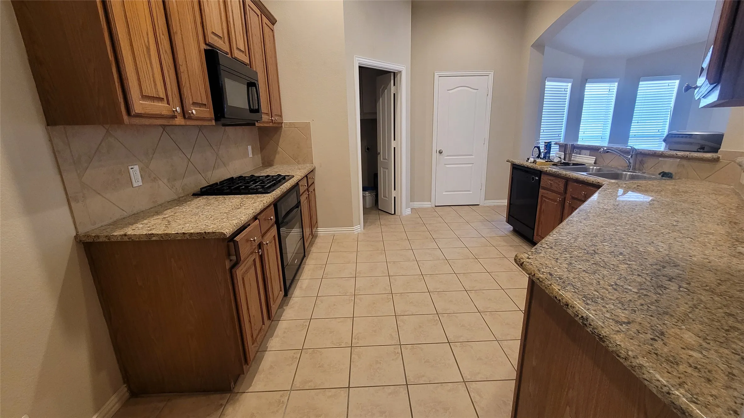 Kitchen featuring wood cabinetry, granite countertops, tile flooring, a built-in microwave, and a gas range