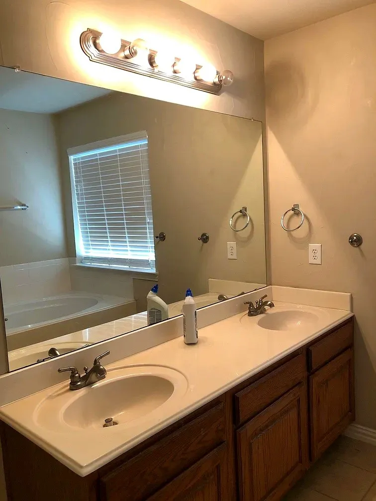 Dual integrated sinks set in a light-toned countertop, above wood-finish cabinetry