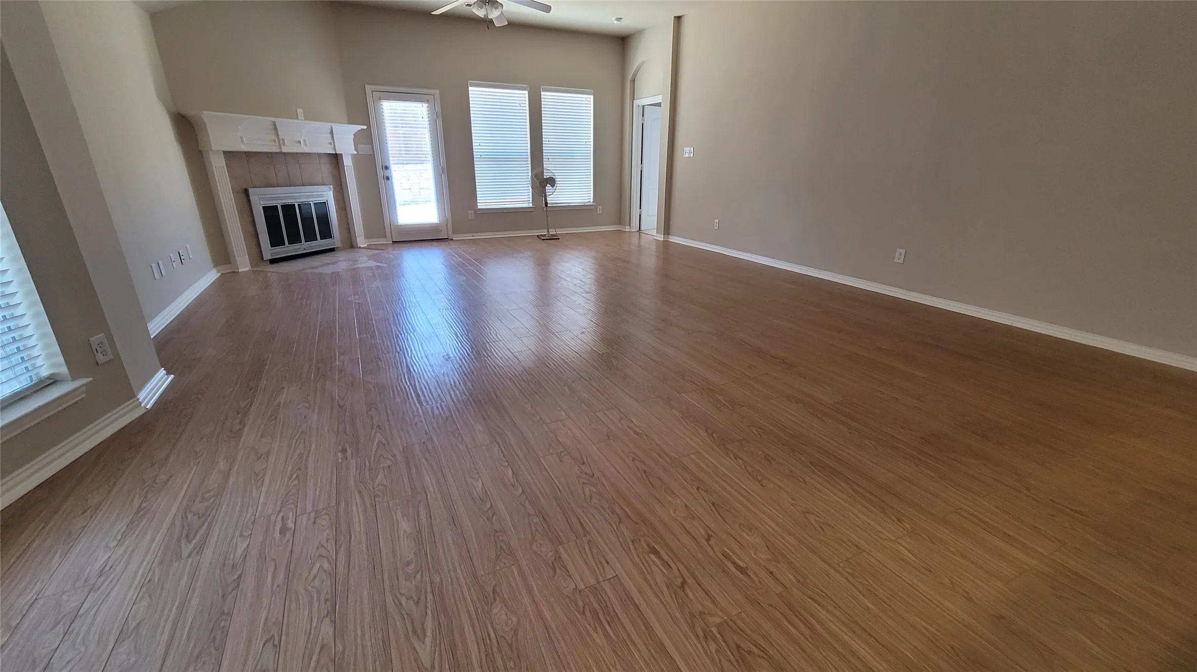Spacious interior featuring wood-finish flooring, a decorative fireplace with mantel, vaulted ceilings, and ample natural light from multiple windows