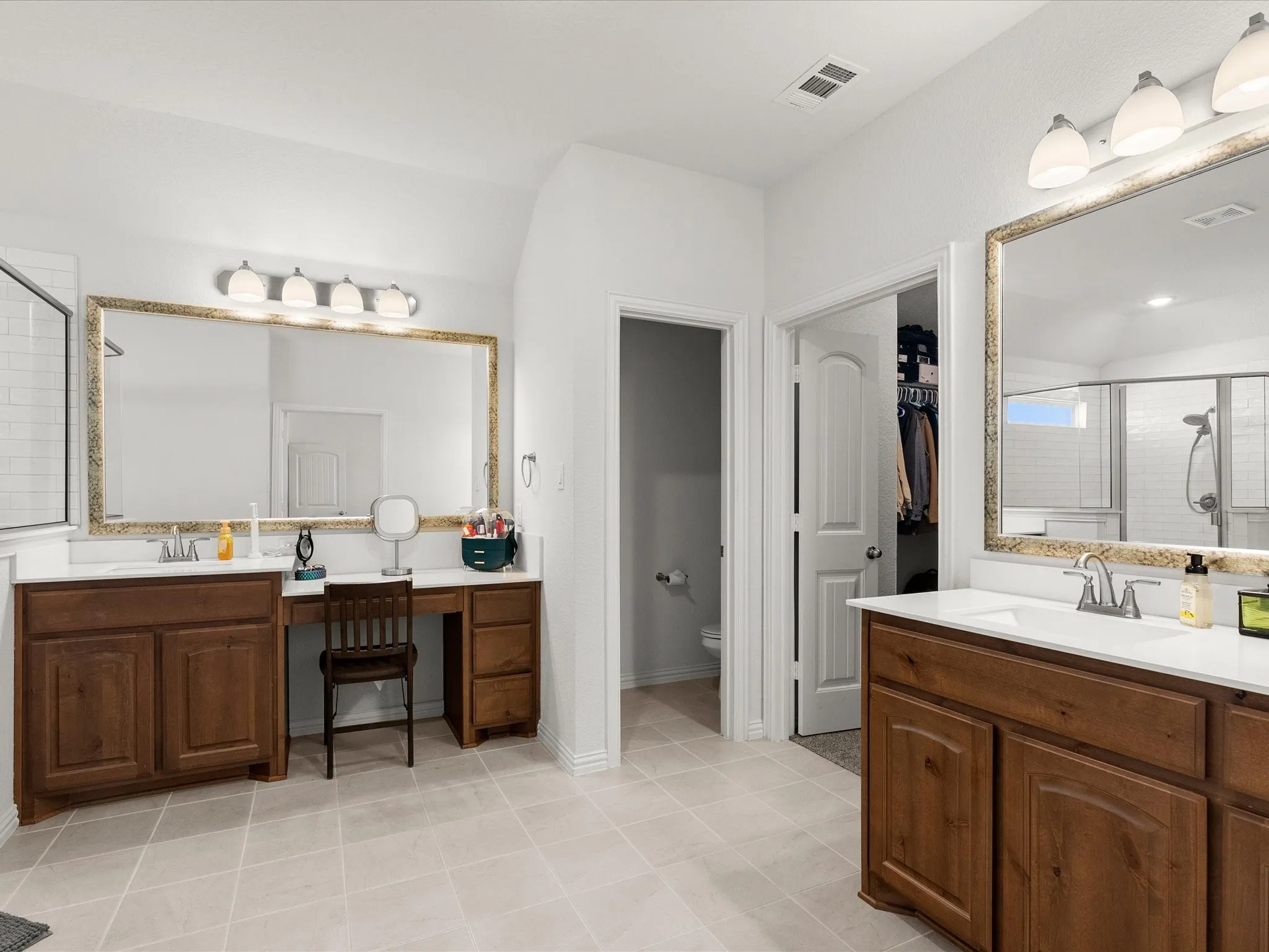 primary bath with double vanities, two sinks, seated vanity area