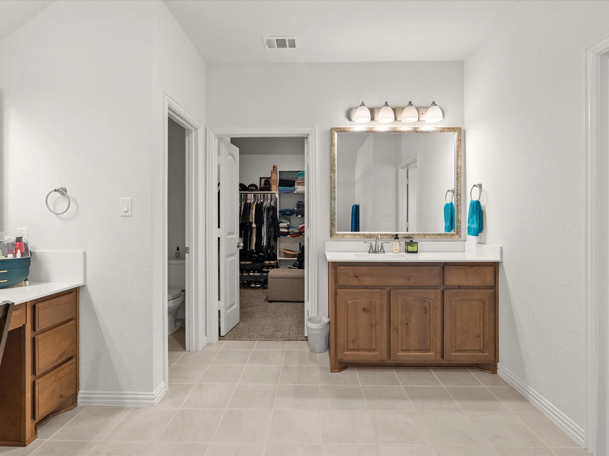 primary bathroom with double vanities, two sinks, seated vanity area