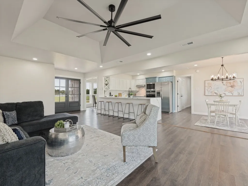Vaulted ceiling with a large ceiling fan, recessed lighting, wood-finish flooring, and double glass-paneled doors