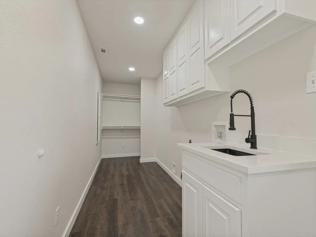 White shaker cabinetry, black sink basin, black pull-down faucet, white countertop, and wood-finish flooring