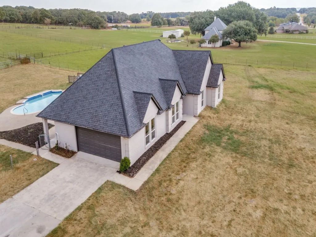 White stucco exterior with dark gray shingles and a concrete driveway