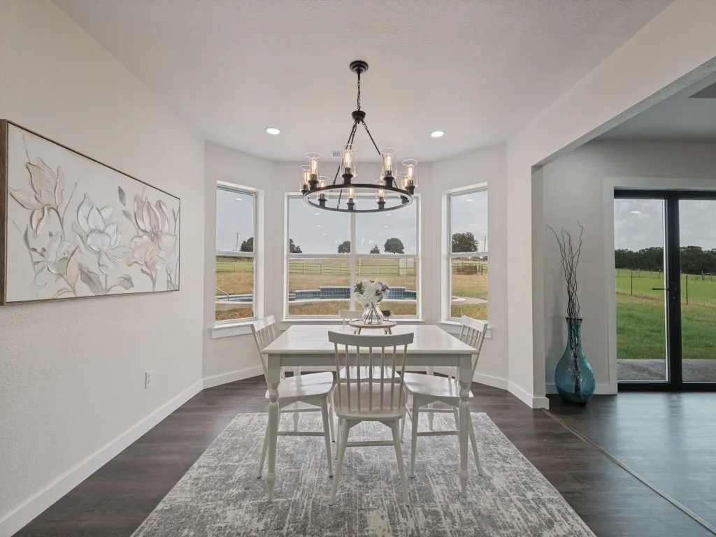 Dining area with multiple windows, wood-finish flooring, and a modern chandelier
