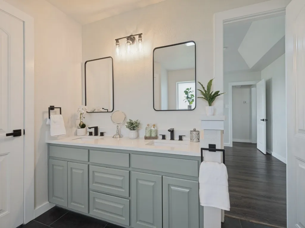Dual vanity with light green cabinetry, white countertops, rectangular undermount sinks, and matte black fixtures