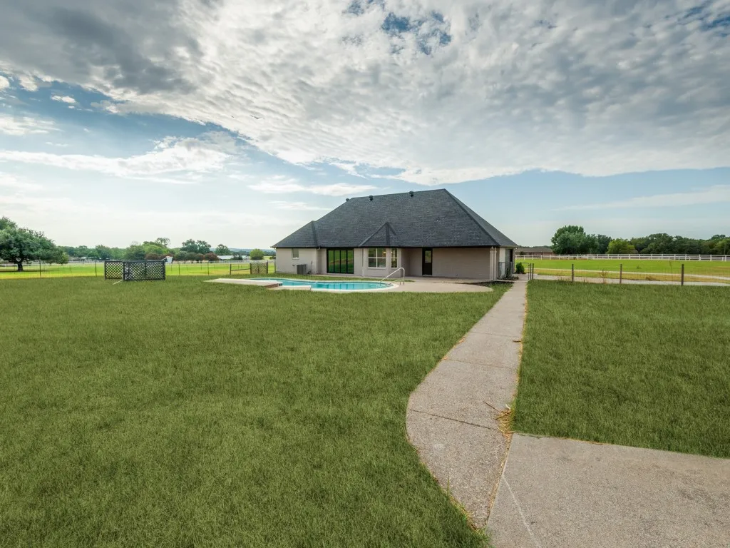 Expansive green lawn with a concrete pathway and a fenced area