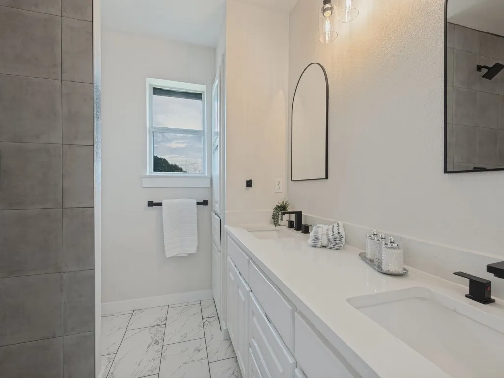 Dual vanity with white cabinetry, integrated sinks, and black fixtures
