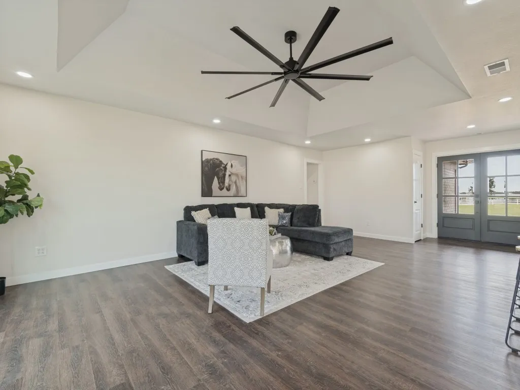 Vaulted tray ceiling with recessed lighting, wood-finish flooring, and double doors with glass panels