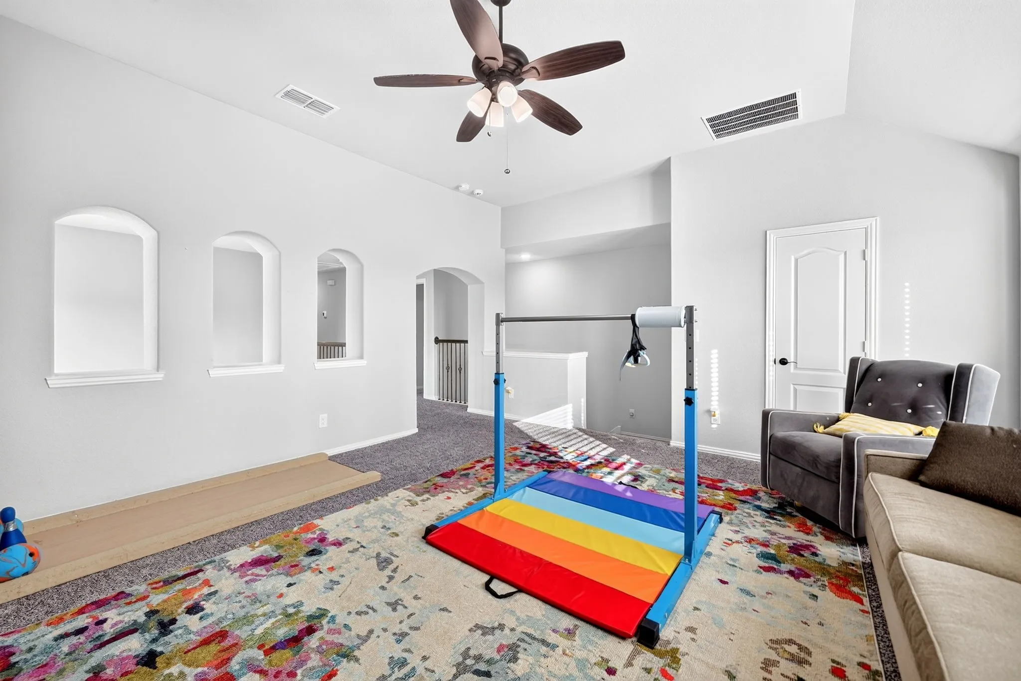 Vaulted ceiling with a ceiling fan, arched wall cutouts, and light gray wall paint