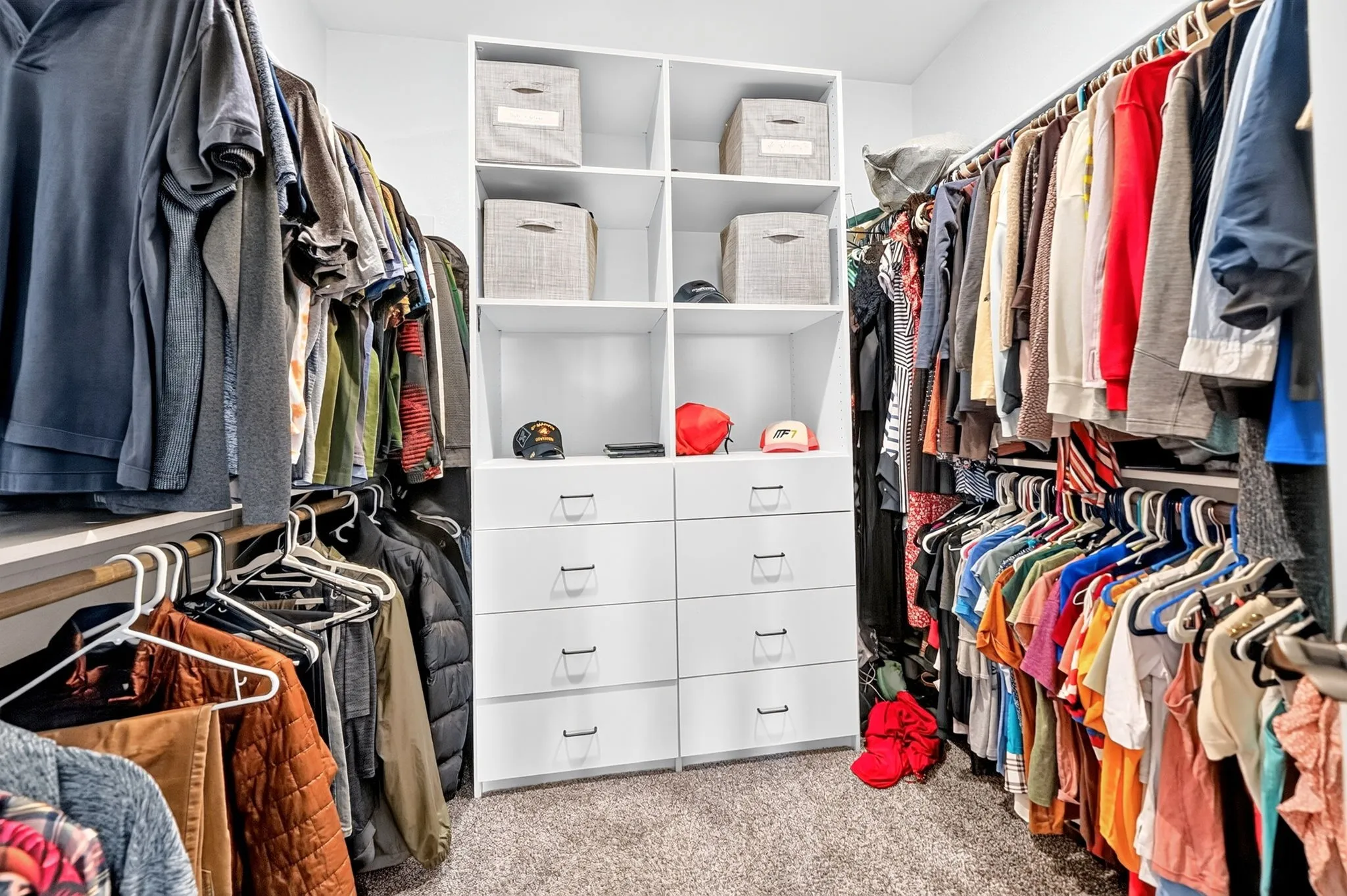 Built-in closet system featuring white shelving, multiple hanging rods, eight integrated drawers, and open storage compartments