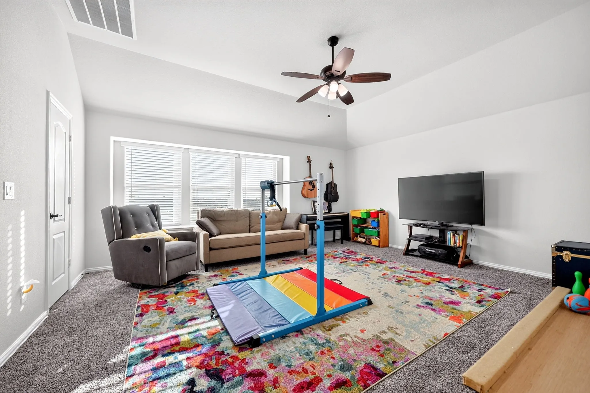 Spacious room featuring vaulted ceilings, a ceiling fan, and multiple windows